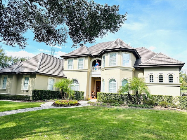 view of front of house featuring a front lawn, a balcony, and stucco siding