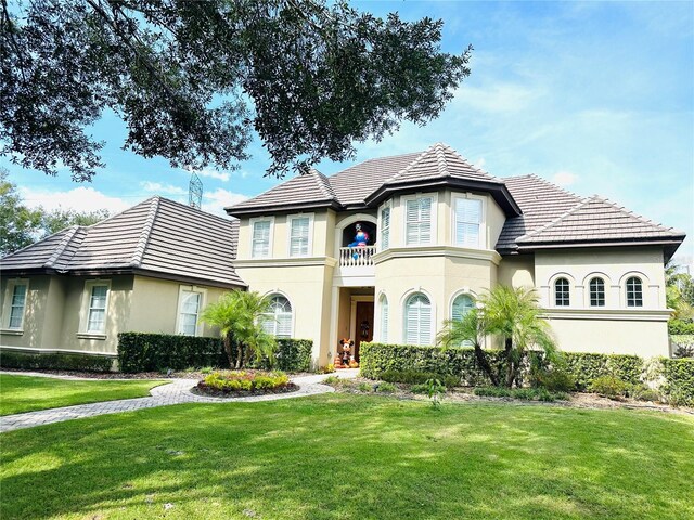 8734 Crestgate Cir, Orlando, FL 32819 - view of front of property featuring a balcony, stucco siding, a front lawn, and a tile roof
