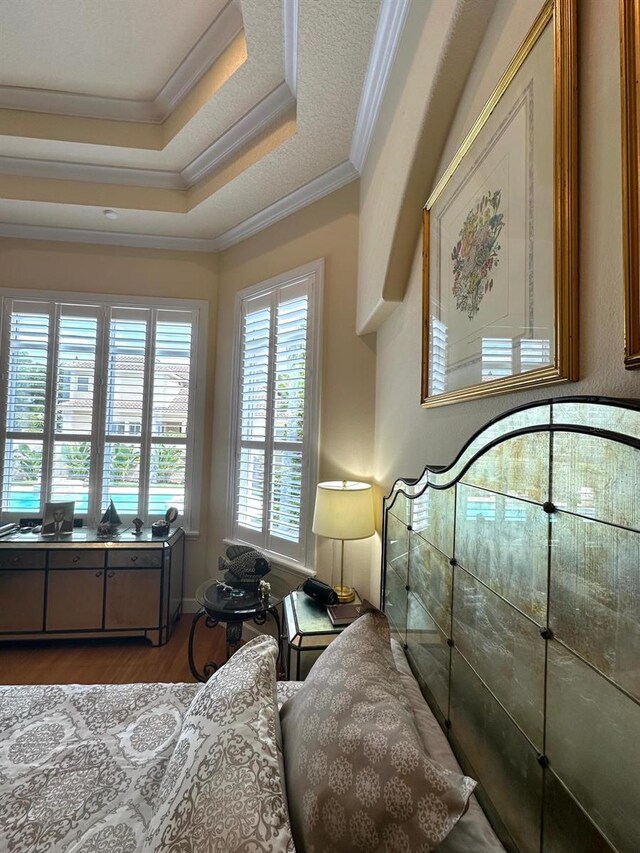 8734 Crestgate Cir, Orlando, FL 32819 - bedroom with ornamental molding, wood finished floors, and a tray ceiling