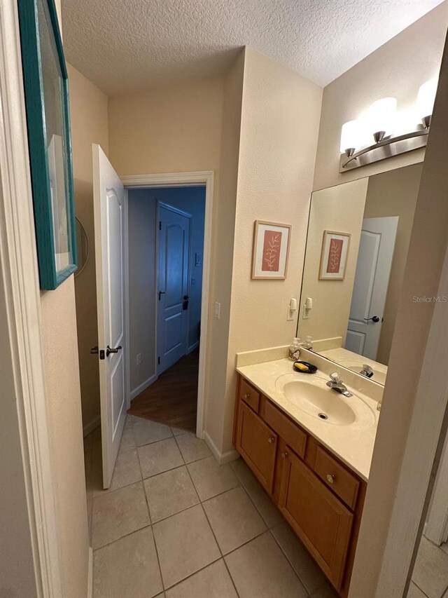 8734 Crestgate Cir, Orlando, FL 32819 - bathroom with a textured ceiling, vanity, tile patterned floors, and baseboards