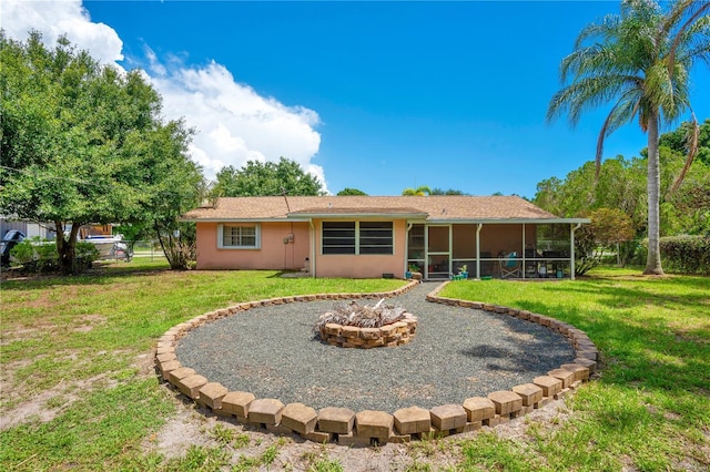 back of house with a fire pit, a lawn, and a sunroom