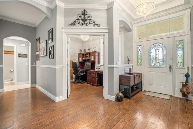 foyer entrance featuring hardwood / wood-style flooring, crown molding, and a notable chandelier