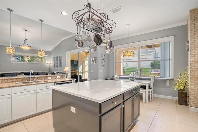 kitchen with white cabinetry, a kitchen island, sink, and light tile patterned floors