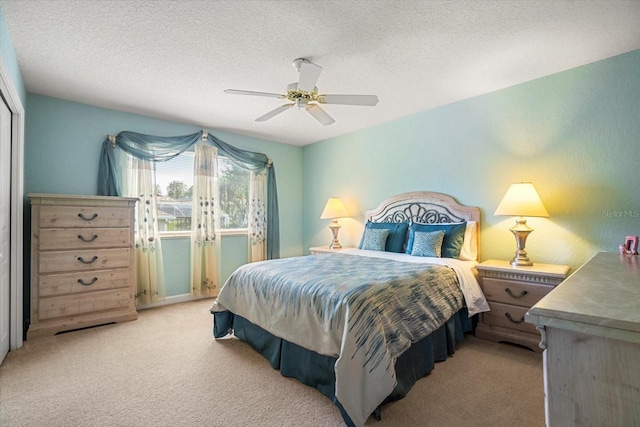 bedroom with light carpet, a textured ceiling, and ceiling fan