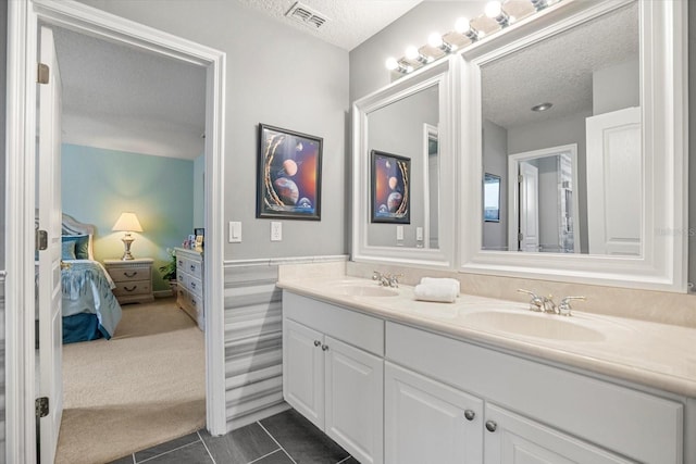 bathroom with tile patterned flooring, vanity, and a textured ceiling