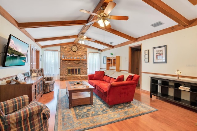 living room featuring a fireplace, ceiling fan, light hardwood / wood-style flooring, and lofted ceiling with beams