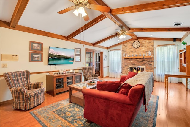 living room with vaulted ceiling with beams, ceiling fan, wood-type flooring, and a brick fireplace