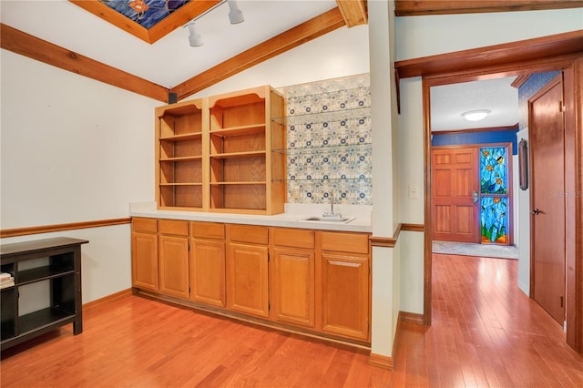 kitchen featuring lofted ceiling, sink, and light hardwood / wood-style flooring