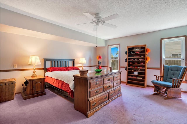 carpeted bedroom featuring ceiling fan and a textured ceiling