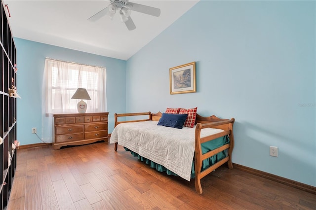 bedroom with ceiling fan, hardwood / wood-style floors, and vaulted ceiling