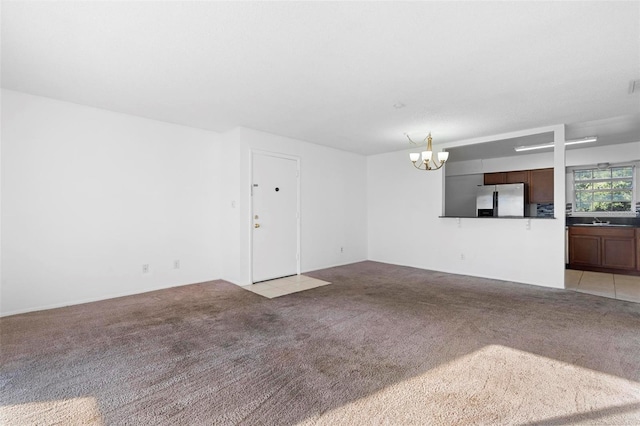 unfurnished living room featuring a notable chandelier, sink, and light colored carpet