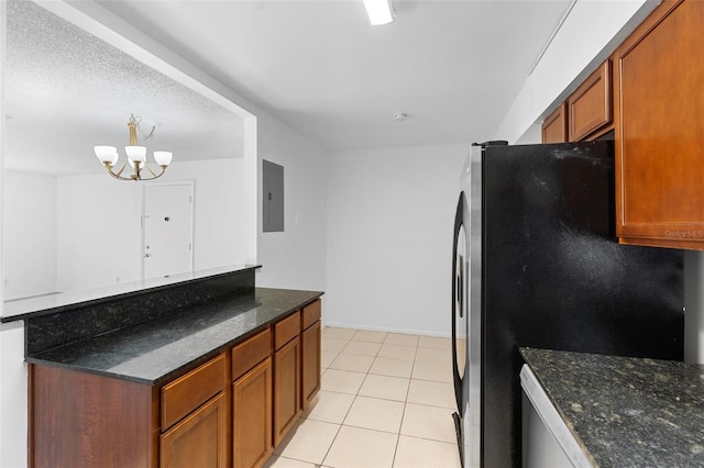 kitchen with electric panel, light tile patterned floors, stainless steel refrigerator, dark stone countertops, and a notable chandelier