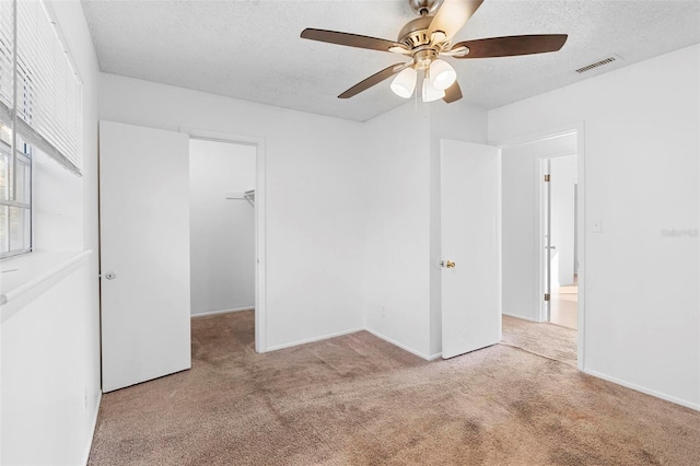 unfurnished room with a textured ceiling, light colored carpet, and ceiling fan