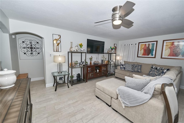 living room with light hardwood / wood-style floors, a textured ceiling, and ceiling fan