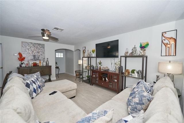 living room featuring a textured ceiling, light hardwood / wood-style flooring, and ceiling fan