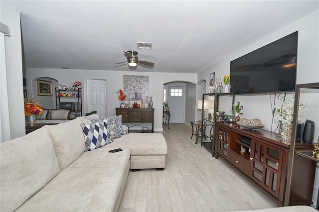 living room featuring light hardwood / wood-style flooring, a textured ceiling, and ceiling fan