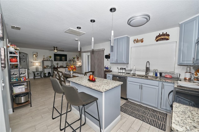 kitchen with a center island, ceiling fan, stainless steel dishwasher, hanging light fixtures, and a kitchen breakfast bar