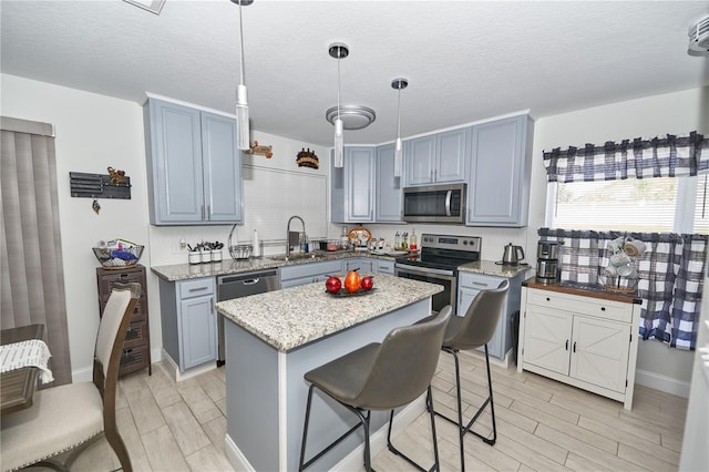 kitchen with stainless steel appliances, a breakfast bar, sink, pendant lighting, and a center island