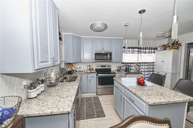 kitchen with a kitchen island, sink, stainless steel appliances, and light tile patterned floors