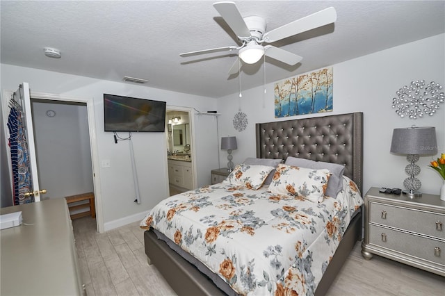 bedroom with ensuite bath, a textured ceiling, ceiling fan, and light hardwood / wood-style floors