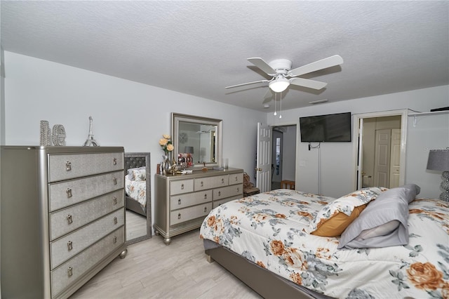 bedroom featuring light hardwood / wood-style floors, a textured ceiling, and ceiling fan