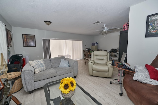 living room with a textured ceiling, ceiling fan, and hardwood / wood-style floors