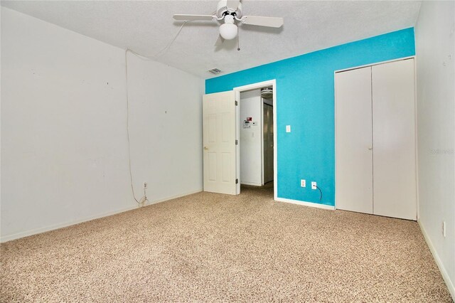 unfurnished bedroom with light carpet, ceiling fan, a closet, and a textured ceiling