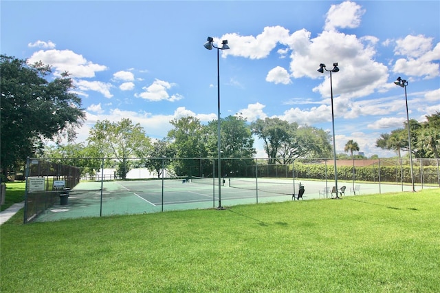 view of sport court with a lawn and fence