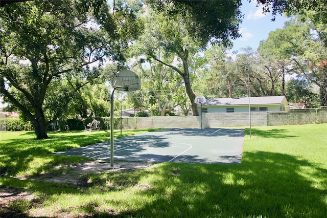 view of basketball court featuring a lawn, community basketball court, and fence