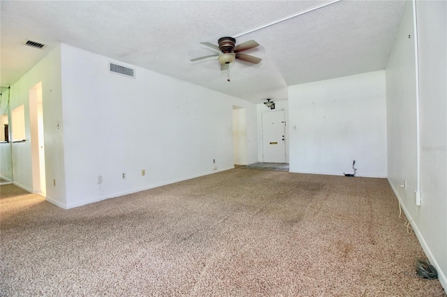 empty room with carpet flooring, a ceiling fan, visible vents, and a textured ceiling