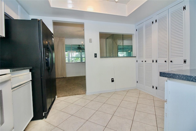 kitchen featuring dark countertops, light colored carpet, light tile patterned floors, white cabinets, and a raised ceiling