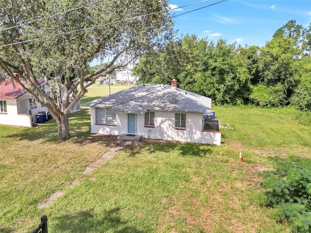 view of front of property with roof with shingles, a chimney, and a front yard