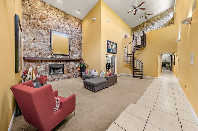 carpeted living room with a textured ceiling, a fireplace, ceiling fan, and a high ceiling