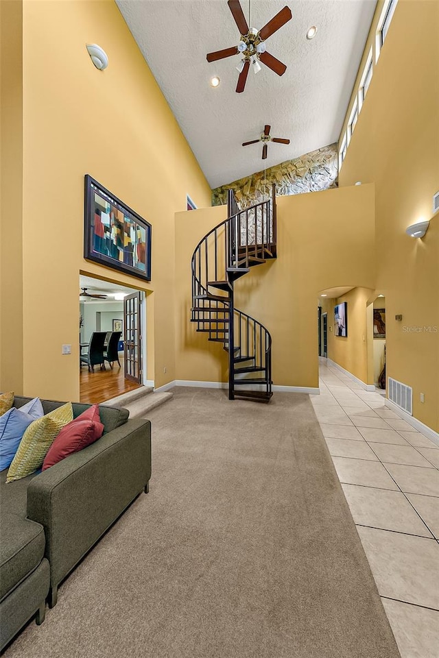 carpeted living room with ceiling fan, a towering ceiling, and a textured ceiling