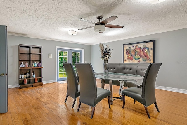 dining room featuring crown molding, ceiling fan, light wood-type flooring, and french doors