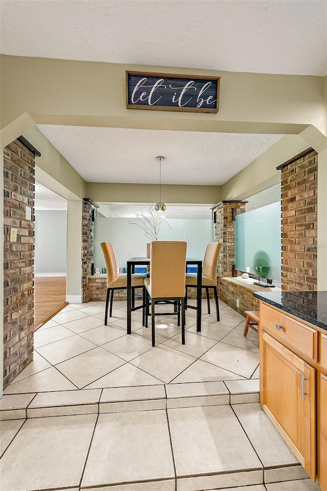 tiled dining space with a textured ceiling and brick wall