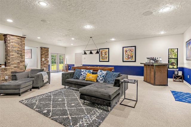 carpeted living room featuring french doors, bar area, and a textured ceiling