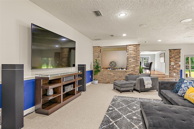 living room with carpet floors, a textured ceiling, and ornate columns