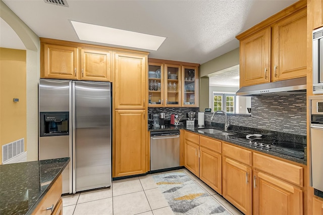 kitchen featuring light tile patterned flooring, sink, dark stone countertops, stainless steel appliances, and backsplash