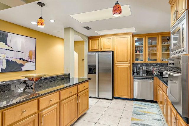 kitchen with pendant lighting, decorative backsplash, dark stone counters, light tile patterned floors, and stainless steel appliances