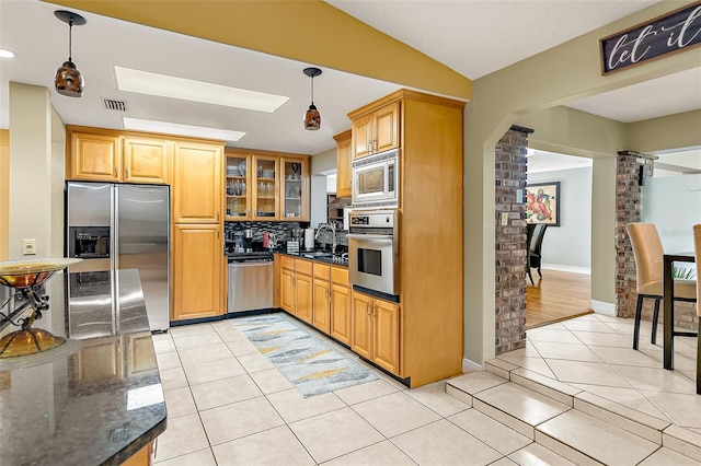 kitchen featuring sink, ornate columns, light tile patterned floors, appliances with stainless steel finishes, and pendant lighting