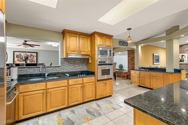 kitchen featuring sink, tasteful backsplash, hanging light fixtures, appliances with stainless steel finishes, and dark stone counters