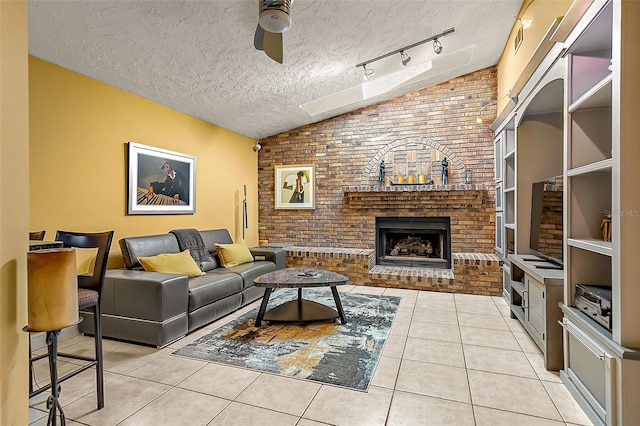 tiled living room with a brick fireplace, vaulted ceiling, a textured ceiling, and ceiling fan