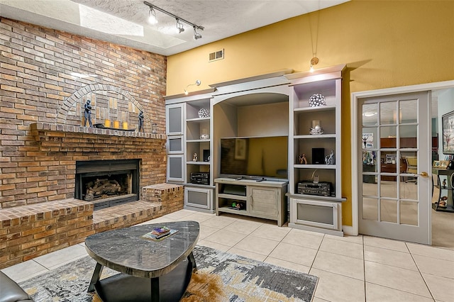 living room with track lighting, a fireplace, a textured ceiling, and light tile patterned floors