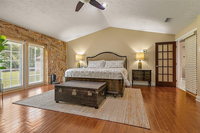 bedroom with ceiling fan, lofted ceiling, dark hardwood / wood-style flooring, and a textured ceiling