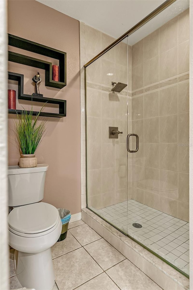 bathroom with tile patterned floors, a shower with door, and toilet