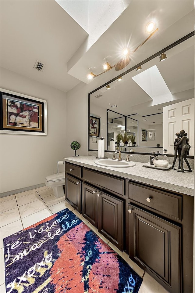 bathroom with vanity, a skylight, and toilet