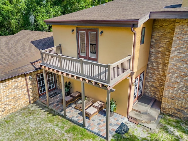 rear view of property with a patio, a balcony, and french doors