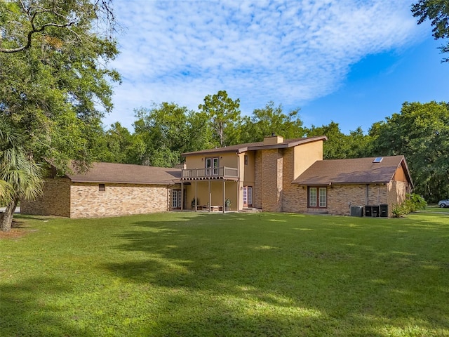 rear view of house featuring cooling unit and a lawn