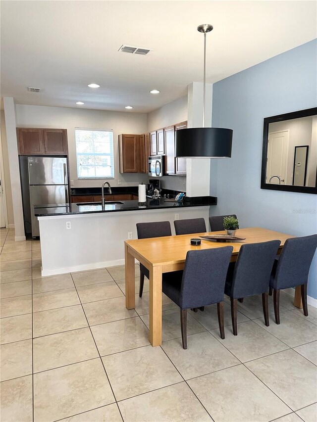 kitchen with kitchen peninsula, sink, light tile patterned floors, and stainless steel appliances